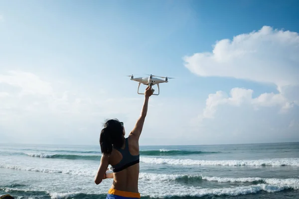 Woman landing or taking off drone which taking photo over sea