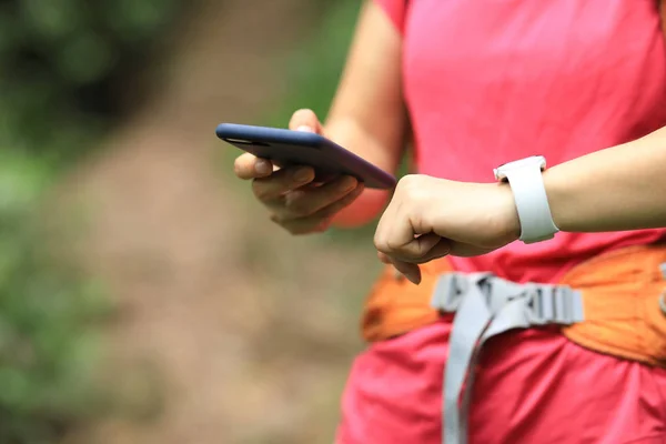 スマートフォンを使用し ハイキング旅行のスマートウォッチ活動データをチェックする女性ハイカー — ストック写真