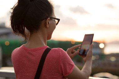 Gün batımında akıllı telefon kullanan kadın Hong Kong