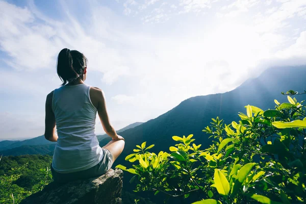 Dağ tepe uçurumun kenarında güneşin doğuşunu meditasyon yoga kadın