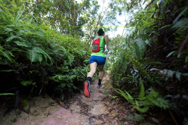 Woman ultra marathon runner running on tropical forest trail