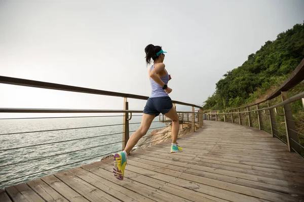 运动的女性赛跑者跑在海滨木板路 — 图库照片