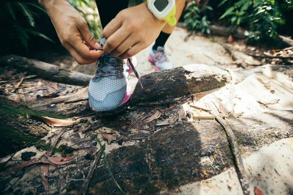 ultra marathon runner tying shoelace on forest trail