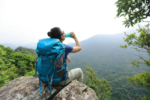 成功的女徒步旅行者享受山巅悬崖边的视野和饮用水 — 图库照片