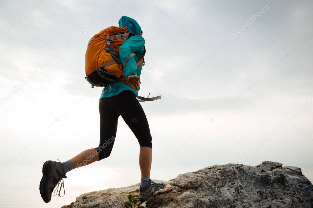 Successful woman hiker running to on seaside mountain peak cliff edge