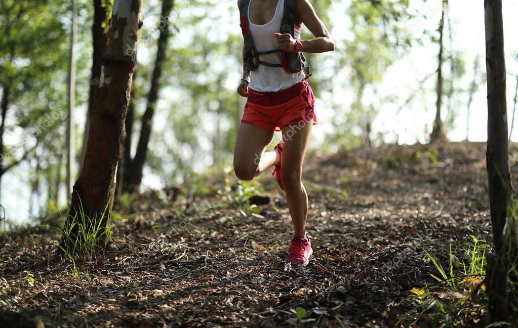 Young fitness woman ultramarathon trail runner running in summer forest 