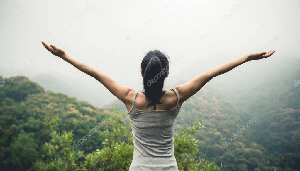 Happy woman with outstretched arms enjoying the view on morning mountain valley