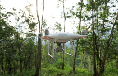 Tropikal ormanda uçan beyaz drone 