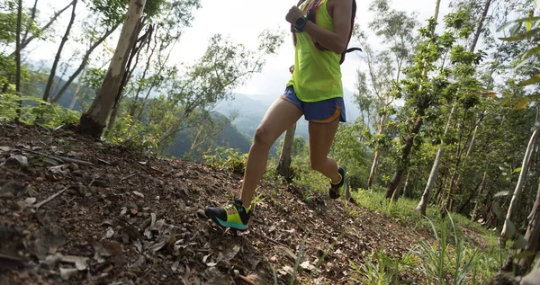 Sportswoman cross country ultra marathon trail runner running in forest
