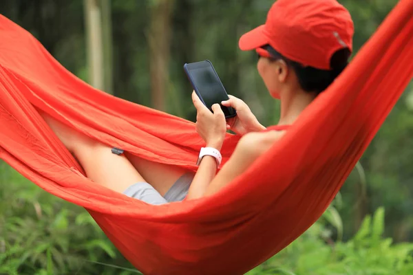 在热带雨林中用智能手机在吊床上放松 — 图库照片