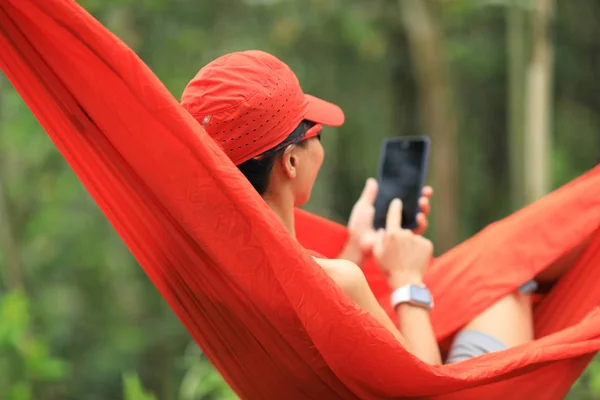 在雨林中用智能手机在吊床上放松 — 图库照片