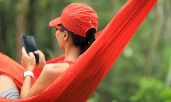 在热带雨林中用智能手机在吊床上放松 — 图库照片