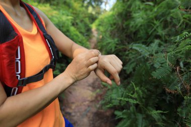 Asyalı kadın ultramaraton koşucusu tropikal yağmur ormanları parkurunda koşmadan önce spor saatini ayarladı
