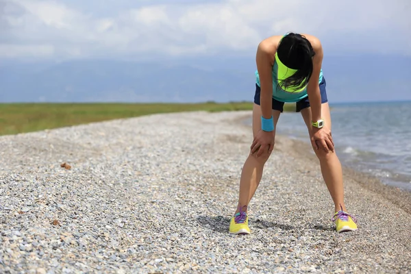 Tired ultra marathon woman runner taking a rest after running hard on seaside