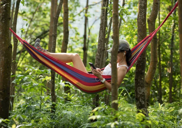 在吊床上放松 在热带雨林中使用智能手机 — 图库照片