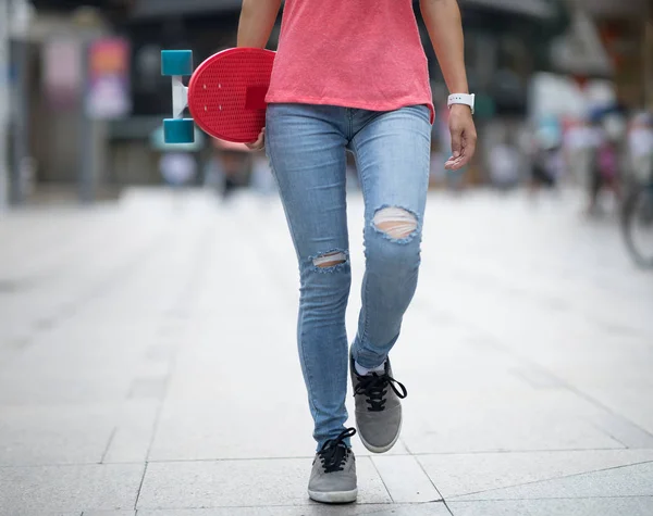 街でスケートボードを手に歩く女性スケートボーダー — ストック写真