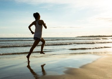 Güneş doğarken plajda koşan fitness kadın koşucusu