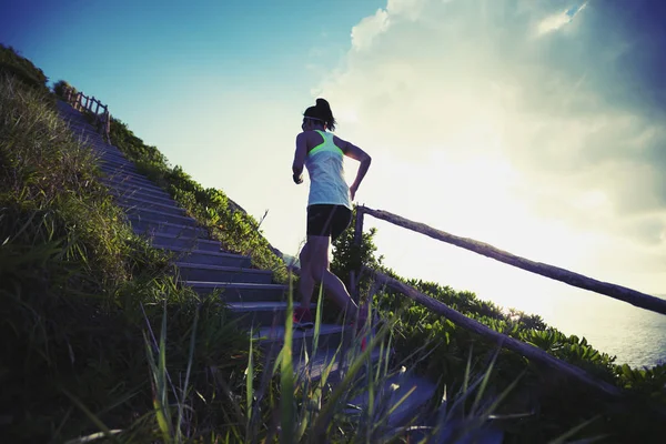 坚定的女子超马拉松选手在海边的楼梯上奔跑 — 图库照片