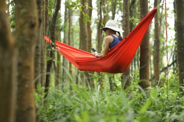 Tropikal yağmur ormanlarında akıllı telefon ile hamakta dinlenen kadın