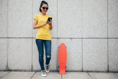 Bir kaykaycı şehirde cep telefonu kullanıyor