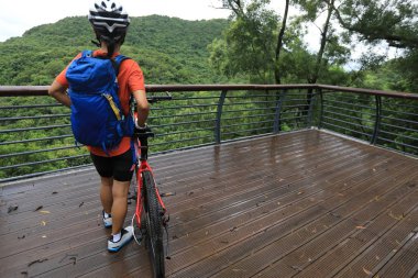 Tropikal yağmur ormanları dağlarında dağ bisikleti sürerken veiw noktasında dinlenen kadın bisikletçi