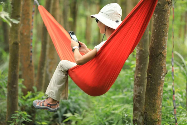 Hamakta Dinlenen Bir Kadın Yağmur Ormanlarında Akıllı Telefonuyla — Stok fotoğraf