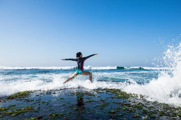 来る強い海の波に直面している海辺の崖の端でヨガの女性瞑想 — ストック写真