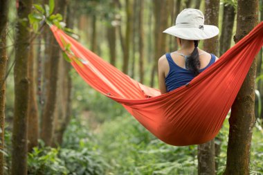 Hamakta dinlenen bir kadın yağmur ormanlarında akıllı telefonuyla
