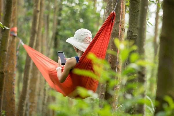 女性は熱帯雨林のスマートフォンでハンモックでリラックス — ストック写真