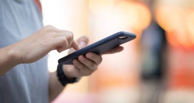 Akşam sokağında akıllı telefon kullanan kişi