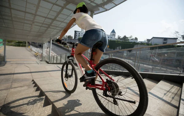 Riding bike down stairs of overpass in city