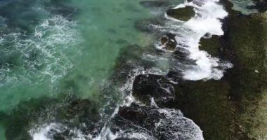 Denizin gün doğumu sahnesi, güneş ışığı okyanusta aydınlatılmış, dalgalar ve taşlar ön planda