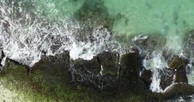 Denizin gün doğumu sahnesi, güneş ışığı okyanusta aydınlatılmış, dalgalar ve taşlar ön planda