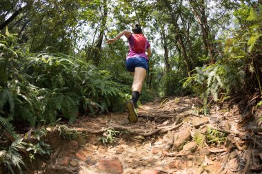 Tropikal orman yolunda koşan ultra maraton koşucusu kadın.