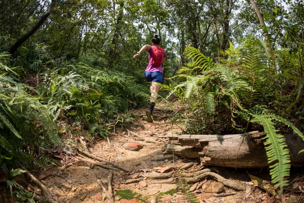 Woman ultra marathon runner running on tropical forest trail