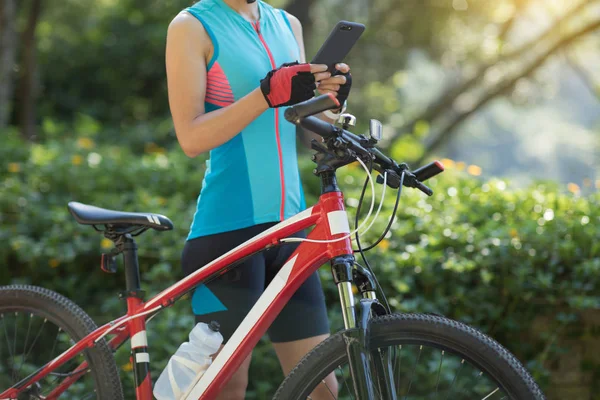 在阳光明媚的日子里骑自行车时 使用智能手机在自行车道上骑行 — 图库照片