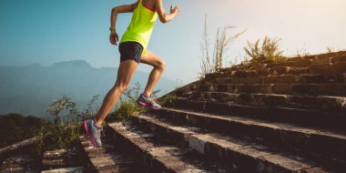 Dağın tepesindeki büyük duvarda koşan genç kadın iz koşucusu