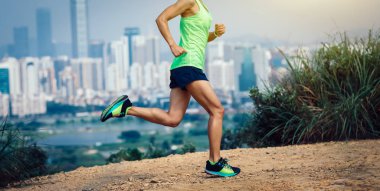 Modern şehrin yanındaki dağlarda koşan kadın ultramaraton koşucusu