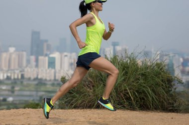 Modern şehrin yanındaki dağlarda koşan kadın ultramaraton koşucusu