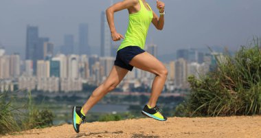 Modern şehrin yanındaki dağlarda koşan kadın ultramaraton koşucusu