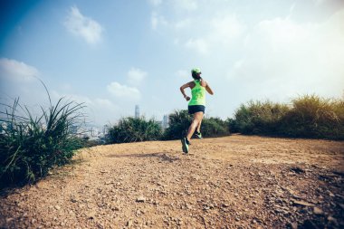 Modern şehrin yanındaki dağlarda koşan kadın ultramaraton koşucusu