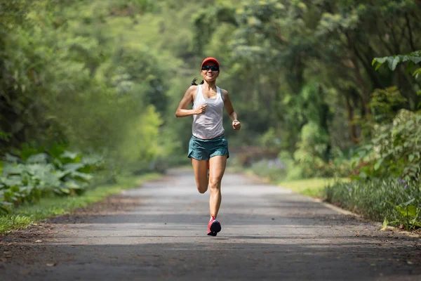 Female runner running at summer park trail.