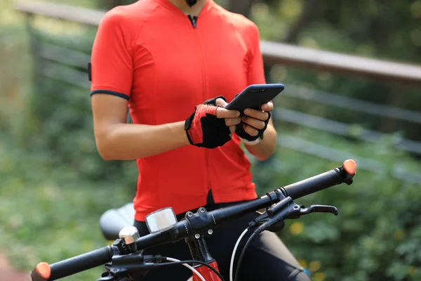 晴れた日に自転車に乗っている間にスマートフォンを使う女性 — ストック写真