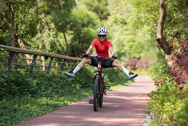 Female cyclist riding mountain bike outdoors in forest