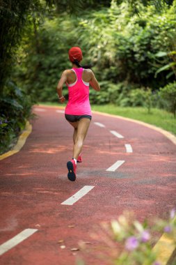 Sağlıklı zinde bir bayan koşucu parkta koşuyor..