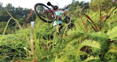 Tropikal orman yolunda bisiklet taşıyan kadın motorcu.