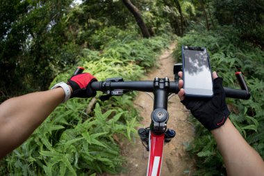 Bisikletçi yağmur ormanlarında bisiklet sürerken akıllı telefon kullanıyor