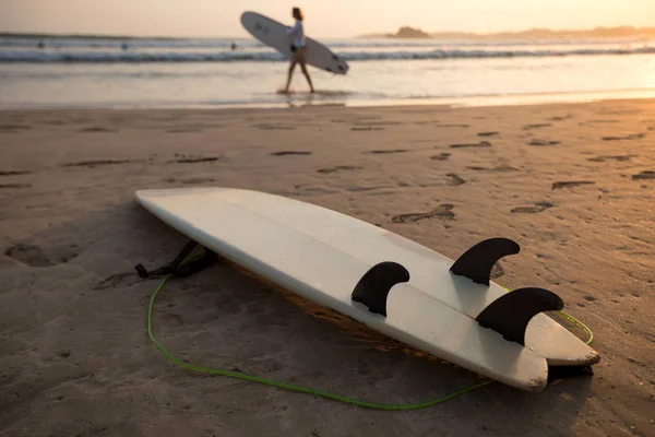 Surfbrett Auf Sand Und Surferin Mit Surfbrett Sonnenuntergang Strand Hintergrund — Stockfoto
