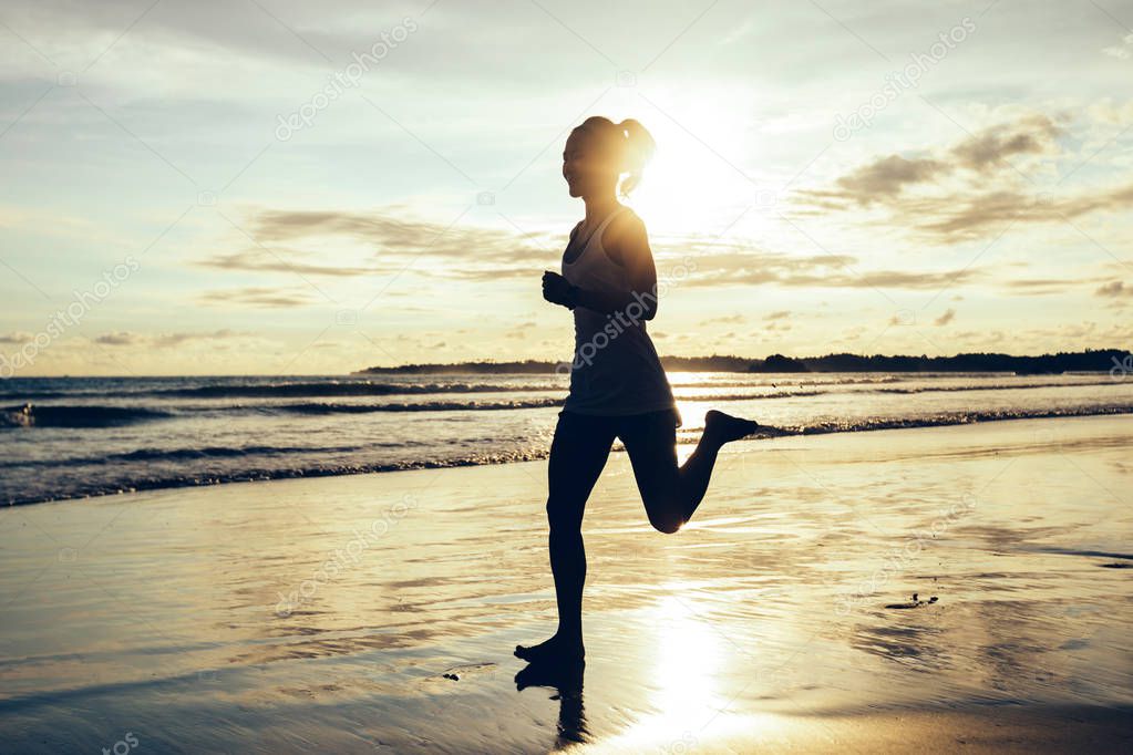 Fitness woman running on sunset beach