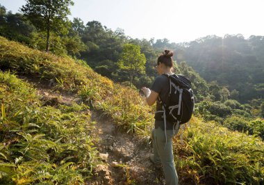 Sonbahar ormanlarında akıllı telefon kullanan kadın yürüyüşçü.